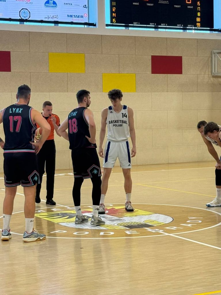 Basketbalisté Basketbal Polabí a BA LYNX Liberecko stojí na rozehrání uprostřed hřiště během utkání v Poděbradech.