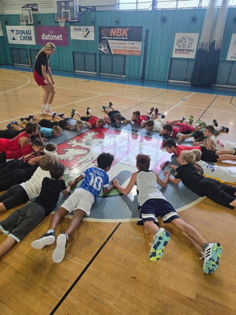 Mladý basketbalista v hale BA Nymburk při driblinku mezi barevnými kužely během tréninku přípravky.