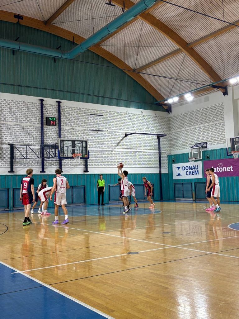 Utkání BA Nymburk U17 proti Basketu Brno na domácí palubovce, hráči stojí v rozestavení při hře na polovině hřiště.